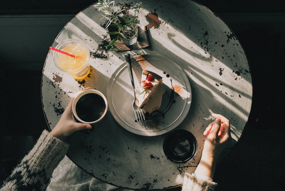 Overhead view of a cozy café table with a slice of cake, coffee, and juice