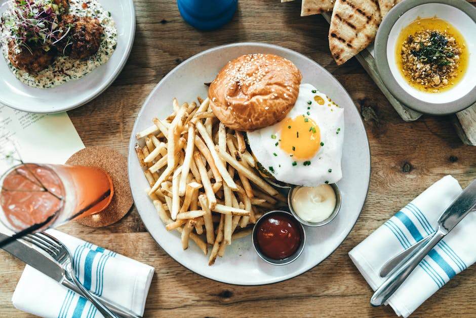 A delicious gourmet burger with fries and a fried egg at a restaurant table