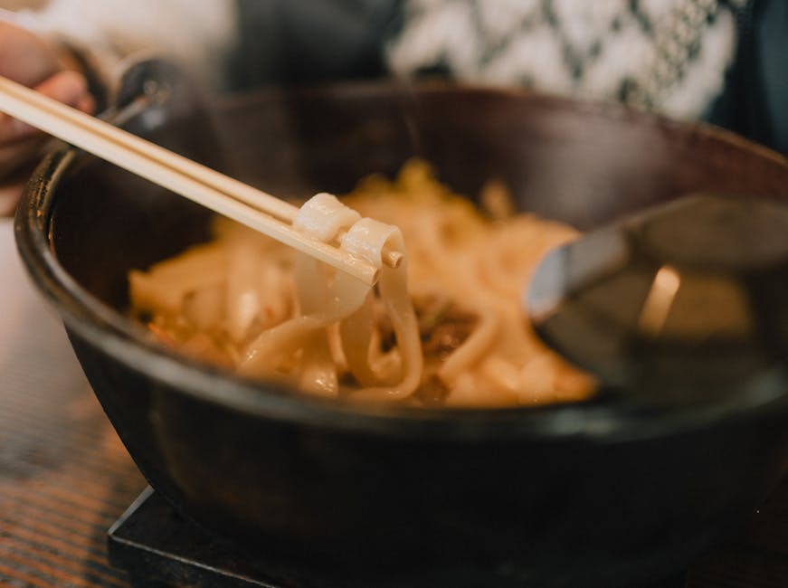 Close-up of steaming udon noodles in a bowl with chopsticks